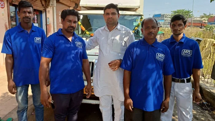 Metro packers and Movers in Bhopa Ahmedabad Team in blue tshirts standing with moving truck